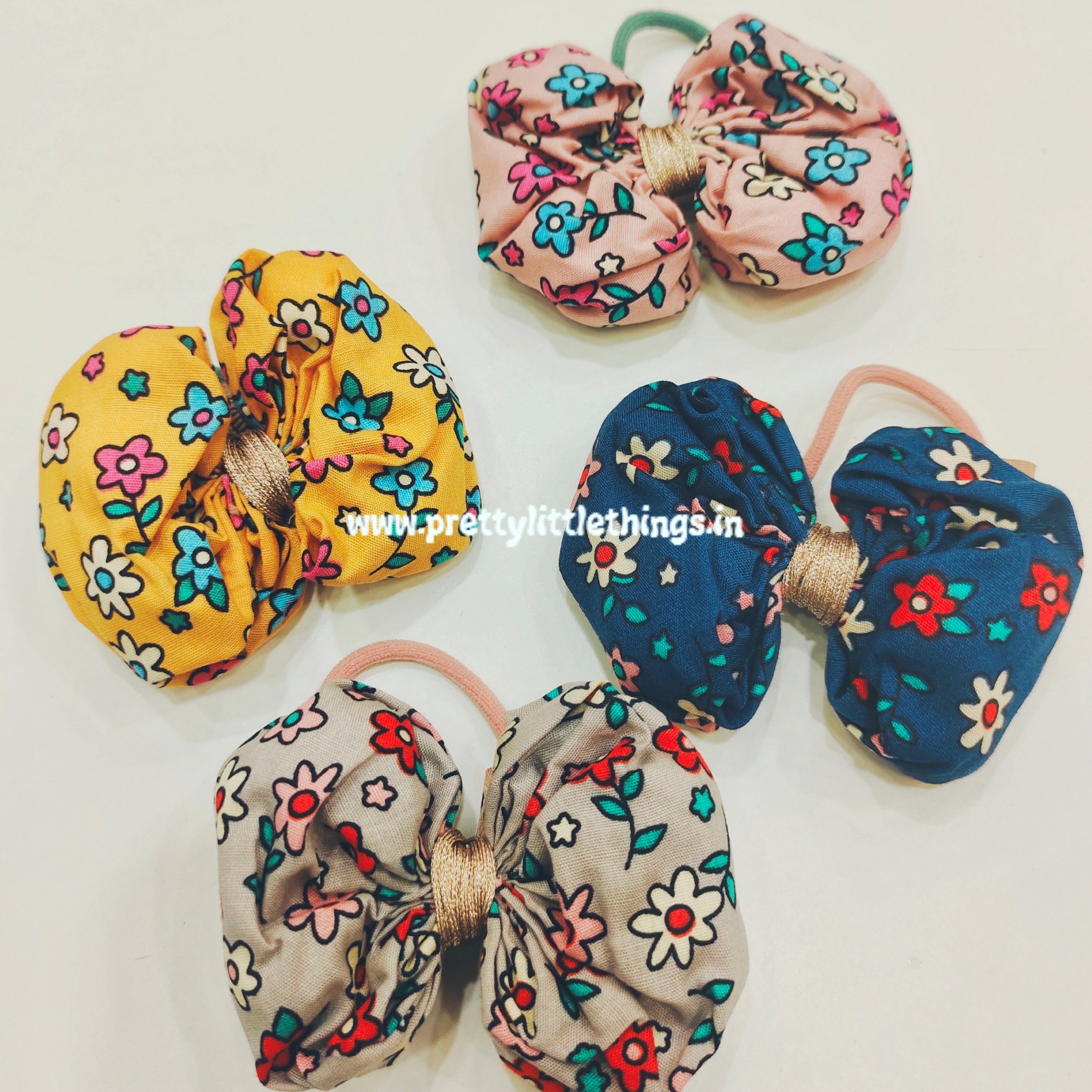 4 floral print bow hair ties in bright colors like yellow, dark blue, grey and pink in a white background