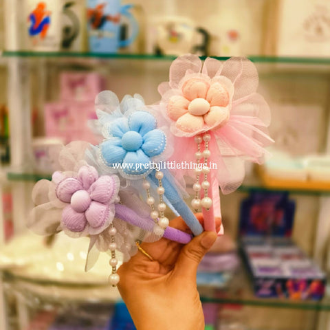 Decorative Fancy Colorful Slim Hair Band with Flower design at the top. Items in the image are pink, purple and blue 