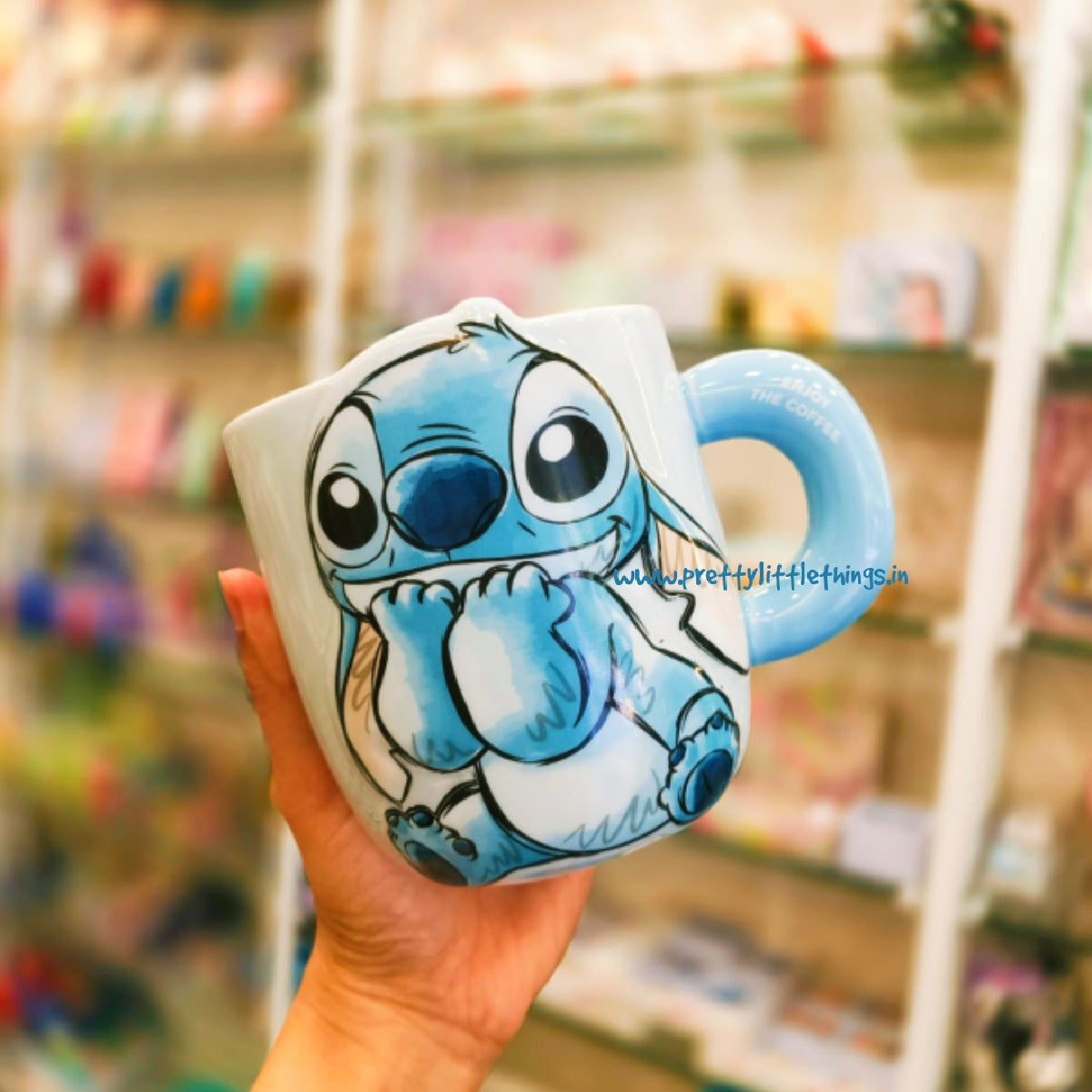 Hand holding a cartoon character ceramic coffee mug in a store setting
