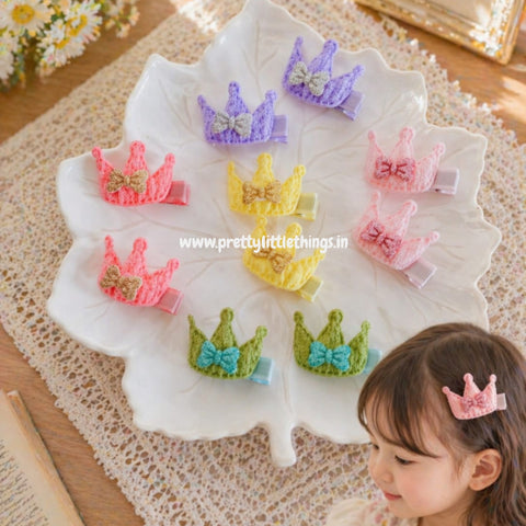 Colorful crown shape hair clips on a decorative stand with a child wearing a pink hair clip.