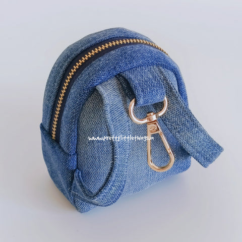 Blue denim coin purse with gold zipper and clasp on a white background