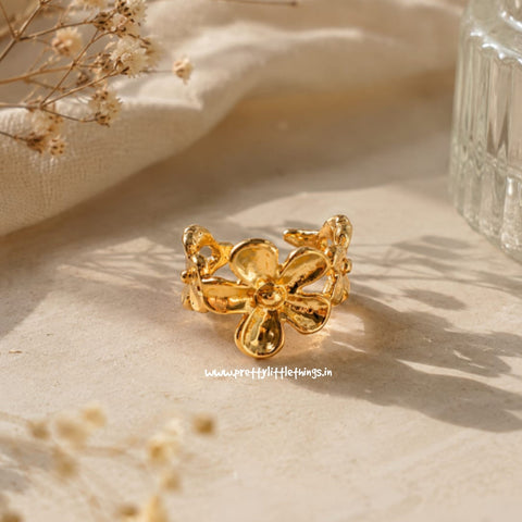 Gold earcuff on a textured beige surface with dried flowers
