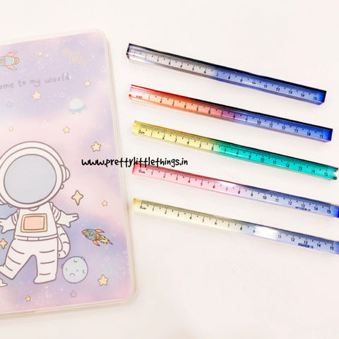 Colorful cube shape rulers on a white surface with a notebook featuring an astronaut design.